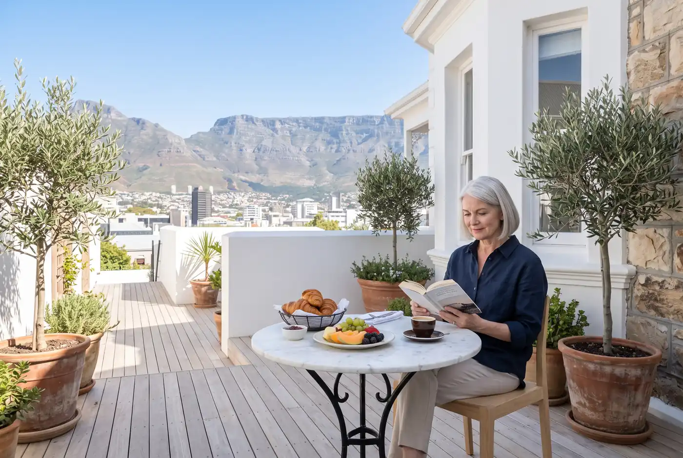 Guest reading at a marble table on the breakfast terrace with Table Mountain behind